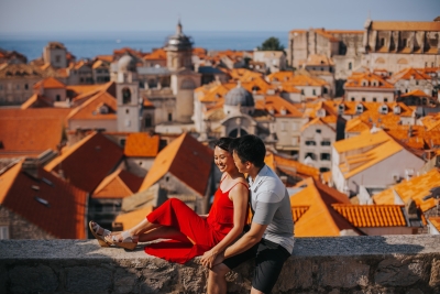 Dubrovnik City Walls in the morning, Old town red roofs, island of Lokrum an sea in the background. Photo shoot with a beautiful couple. Red dress