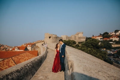 Dubrovnik City Walls in the morning, Old town red roofs and  Minceta tower in the background. Photo shoot with a beautiful couple. Red dress, Game of Thrones